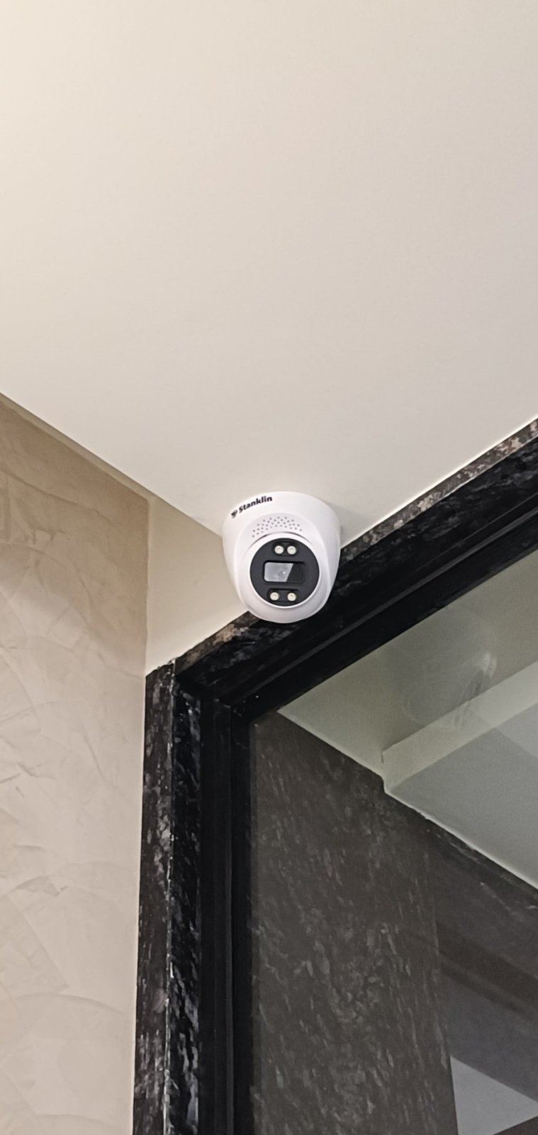 Indoor dome camera mounted at the top corner of a glass door frame