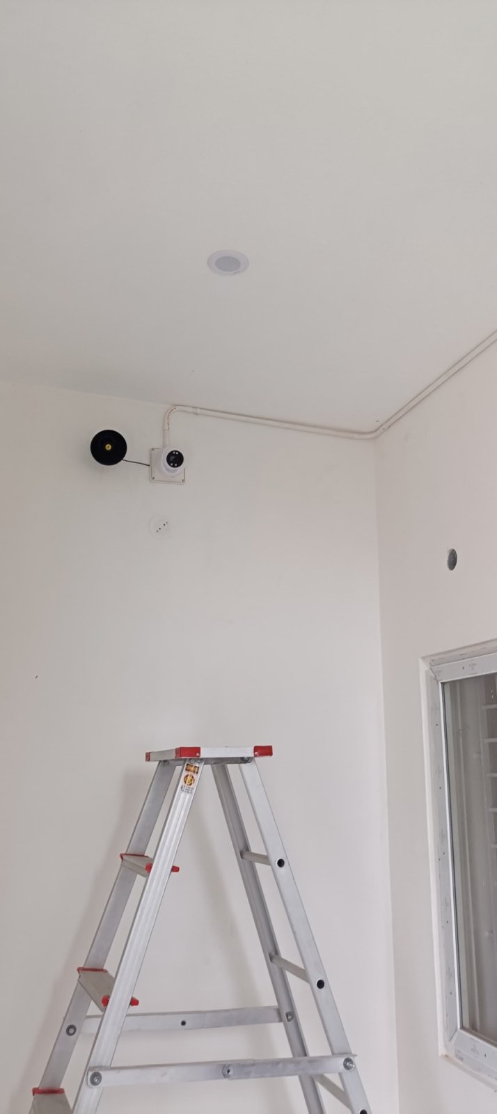 Indoor dome camera and speaker mounted high in a room corner