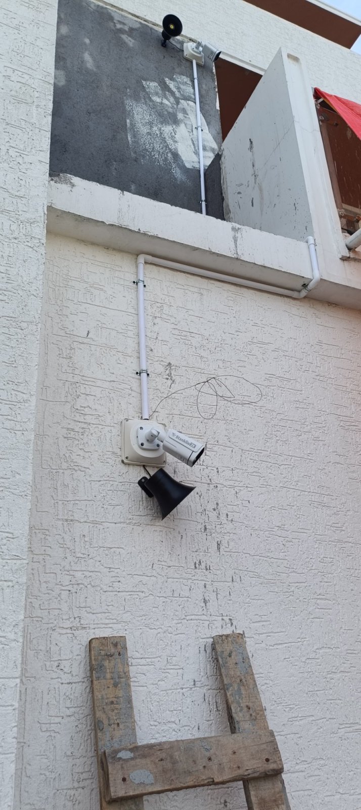 AI CCTV cameras with siren speakers on two levels of a building, with cable in white conduit