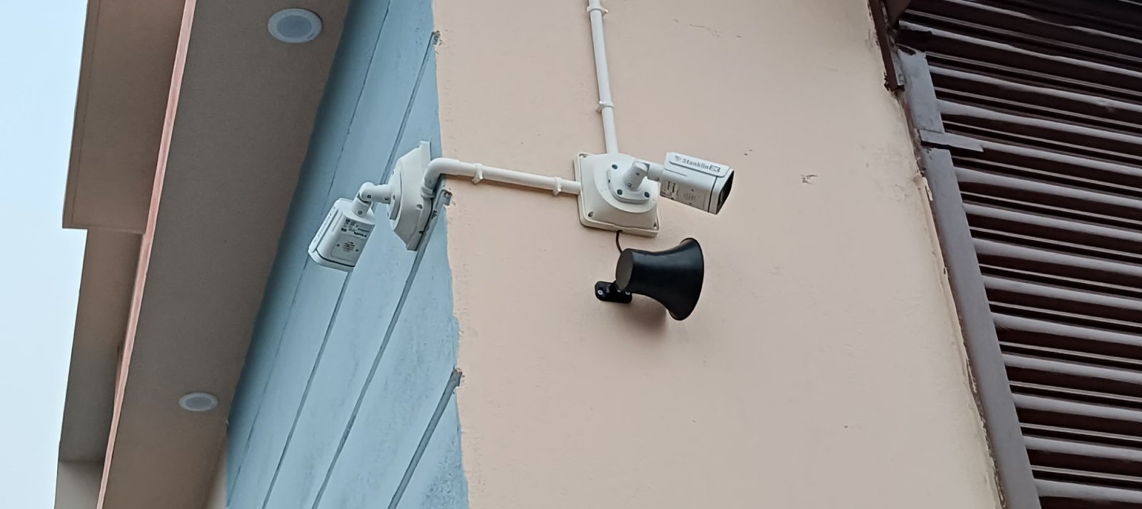 Two Stanklin cameras and a siren speaker at the corner of a building with conduit between them